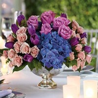 An impeccable centerpiece filled with colorful hydrangea, roses and tulips perfect for a funeral visitation or gathering at a home.